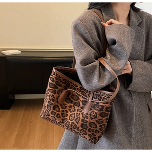 Leopard print tote bag with brown leather handles worn by a model in a stylish interior