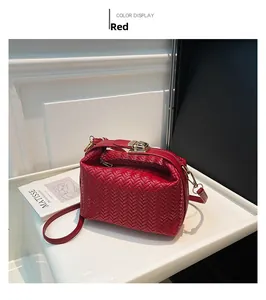 Detail of red woven texture on a minimalist shoulder bag with golden metal buckle clasp