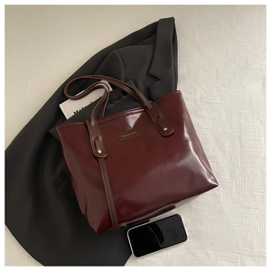 Détail d'un cabas bordeaux foncé avec clous dorés et logo tendance sur le cuir