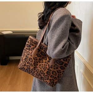 Detail view of large leopard print tote bag with brown leather handles on shoulder