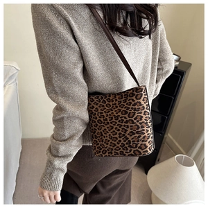 Close-up of leopard print crossbody bag with premium brown leather strap on model