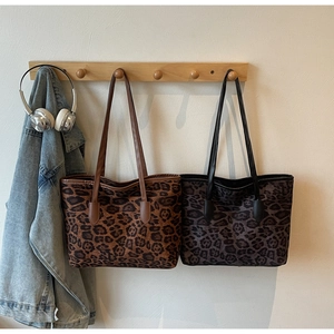Detail of leopard print tote bags in brown and grey hanging in a lifestyle setting
