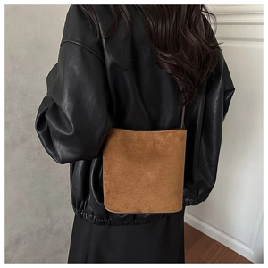 Detail of a brown suede bucket bag texture paired with a black leather jacket