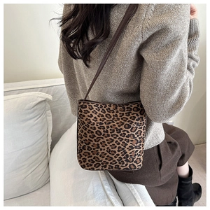 Detail of leopard print bucket bag with brown leather strap worn over the shoulder