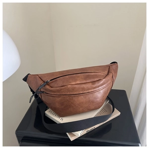 Close-up of brown faux leather crescent bag with adjustable nylon strap and black zipper