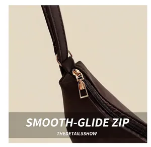 Close-up of smooth gold metal zipper and stitching on dark brown vintage tote bag