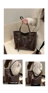 Detail of dark brown glossy tote bag with gold lettering and long shoulder straps