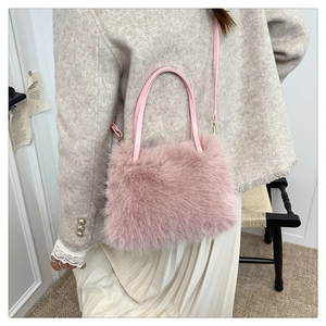 Detailed side view of a plush pink faux fur handbag with a slim shoulder strap
