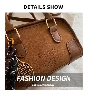 Dettaglio borsa Boston marrone con logo DTN in rilievo e ciondolo da tennis