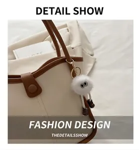 Detail view of a white fluffy monster charm with legs on a beige contrast tote bag