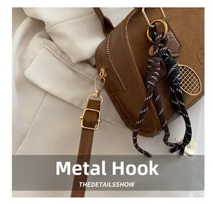 Dettaglio del gancio in metallo dorato e pelle marrone su una borsa vintage