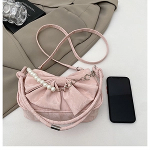 Détail du sac à main rose avec nœud, chaîne de perles et tissu texturé élégant