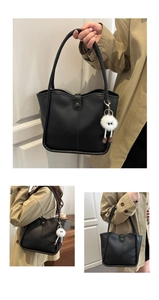 Detail of black faux leather tote bag with snap closure and white plush eye charm