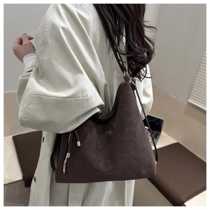 Détail du sac cabas en daim marron foncé avec cordon à franges et fermeture sur le mannequin