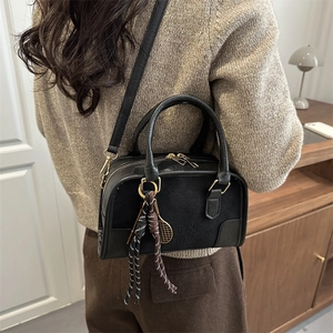 Retro black crossbody bag with TNTN lettering and tennis racket charm worn by a model