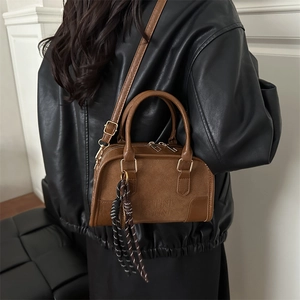 Brown vintage leather shoulder bag with embossed logo and decorative woven tassel