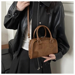 Close-up of retro brown Boston bag with embossed logo and suede leather texture details