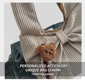 Detail eines süßen braunen Teddybär-Plüsch-Anhängers an einer beigen Cordtasche