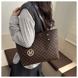 Détail du sac cabas vintage avec motif monogramme M et pendentif métallique doré chic