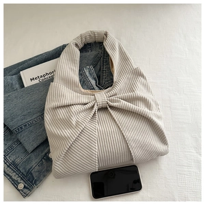 Close-up of beige corduroy tote bag with large decorative bow and soft ribbed texture