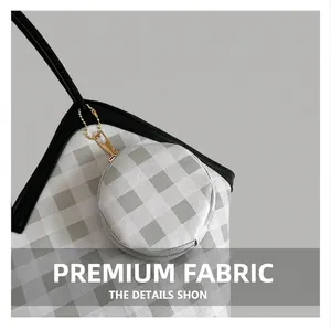 Detail view of grey and white checkered tote bag fabric with gold zipper and charms