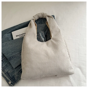 Detail of light beige corduroy tote bag featuring ribbed texture and soft pleated handles