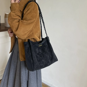 Bolso tote de ante negro con correa trenzada mostrado en un ambiente de estilo de vida