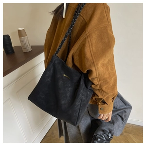 Detailed view of black frosted tote bag with woven rope strap and gold logo branding