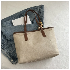Détail du sac cabas en toile avec anses en cuir marron et foulard en soie décoratif