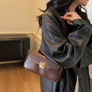 Minimalist deep brown underarm bag with gold lock buckle and smooth finish on model