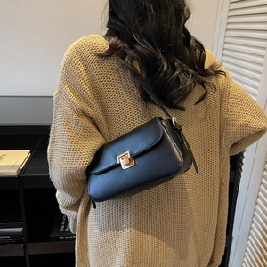 Minimalist black leather underarm bag with gold metal buckle on model back