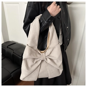 Detail der beigen Cord-Tasche mit weicher Textur und großer dekorativer Schleife