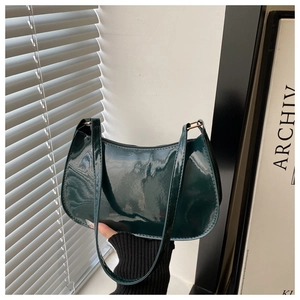 Macro view of dark green patent leather baguette bag with high-gloss finish and slim strap