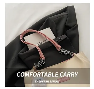 Détail du sac fourre-tout beige avec poignées roses, chaîne argentée et pompon blanc sur tissu