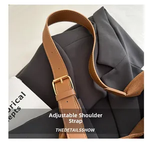 Detail of adjustable brown leather shoulder strap with a polished golden metal buckle