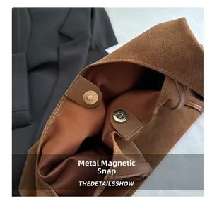 Close-up of brown suede tote bag featuring secure magnetic snap closure and textile lining