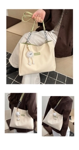Détail du sac cabas blanc avec étiquette FASHION verte et bandoulière chaîne et pompon doux