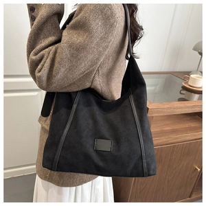 Détail du grand sac hobo noir en daim mat avec lanières en cuir et empiècement