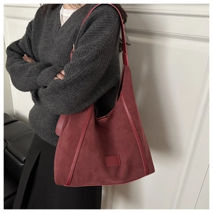 Détail du grand sac cabas bordeaux en suédine avec finitions en cuir porté par un mannequin
