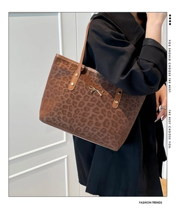 Detail of leopard print tote bag with golden bow hardware and studded brown strap