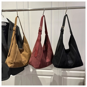 Hanging display of large canvas tote bags in yellow, red, and black with leather patches