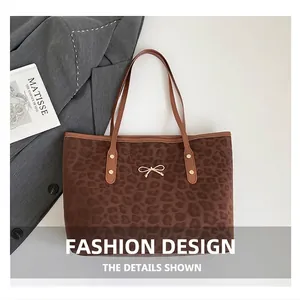 Detail view of leopard print tote bag with golden bow ornament next to a fashion magazine