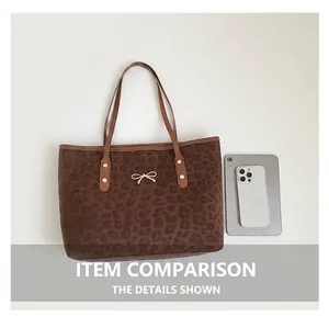 Detail of leopard print tote bag with golden bow hardware and rivet reinforced strap