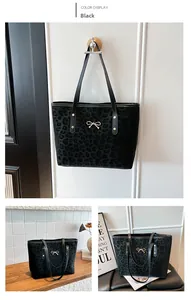 Macro detail of black leopard print tote bag with a golden bow metal buckle accessory