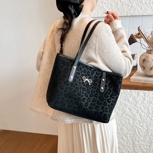 Chic leopard print tote bag with silver bow accent on a model in a minimalist interior