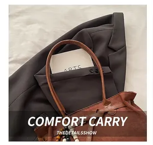 Grand sac cabas en daim marron foncé avec breloque en perles de bois sur fond épuré