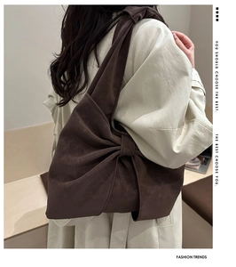 Detail view of coffee brown oversized bow-shaped shoulder bag in soft suede material