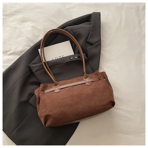 Détail du sac cabas vintage en daim marron avec bandoulière sur un blazer gris