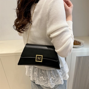Classic black trapezoid shoulder bag with gold chain strap and metallic M buckle closure