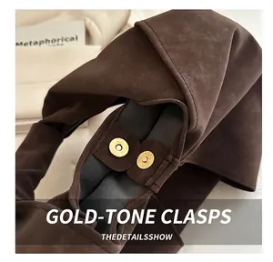 Close-up of golden magnetic clasp on brown suede handbag with neat stitching detail